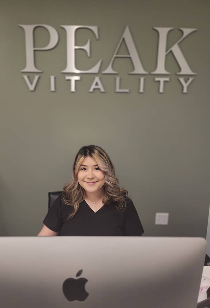 Isabelle Apodaca sitting at the front desk of our Peak Vitality office